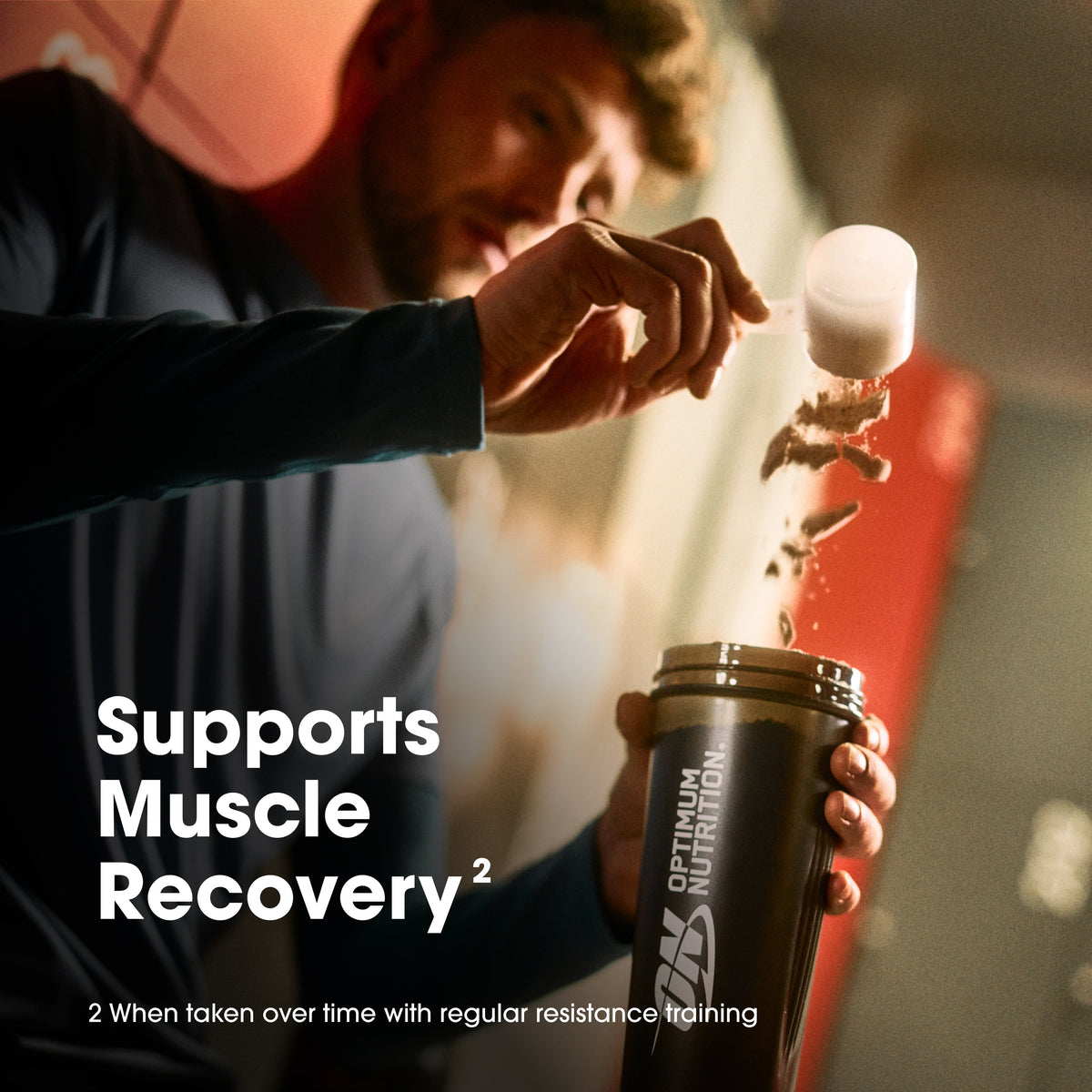 Person pouring a supplement into a shaker bottle with Optimum Nutrition branding, set against a blurred indoor background.