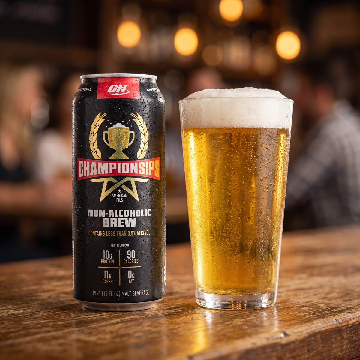 An Optimum Nutrition Champions Non-Alcoholic Brew can sits on a wooden table next to a glass of golden beer with white foam, set against a blurred pub background.